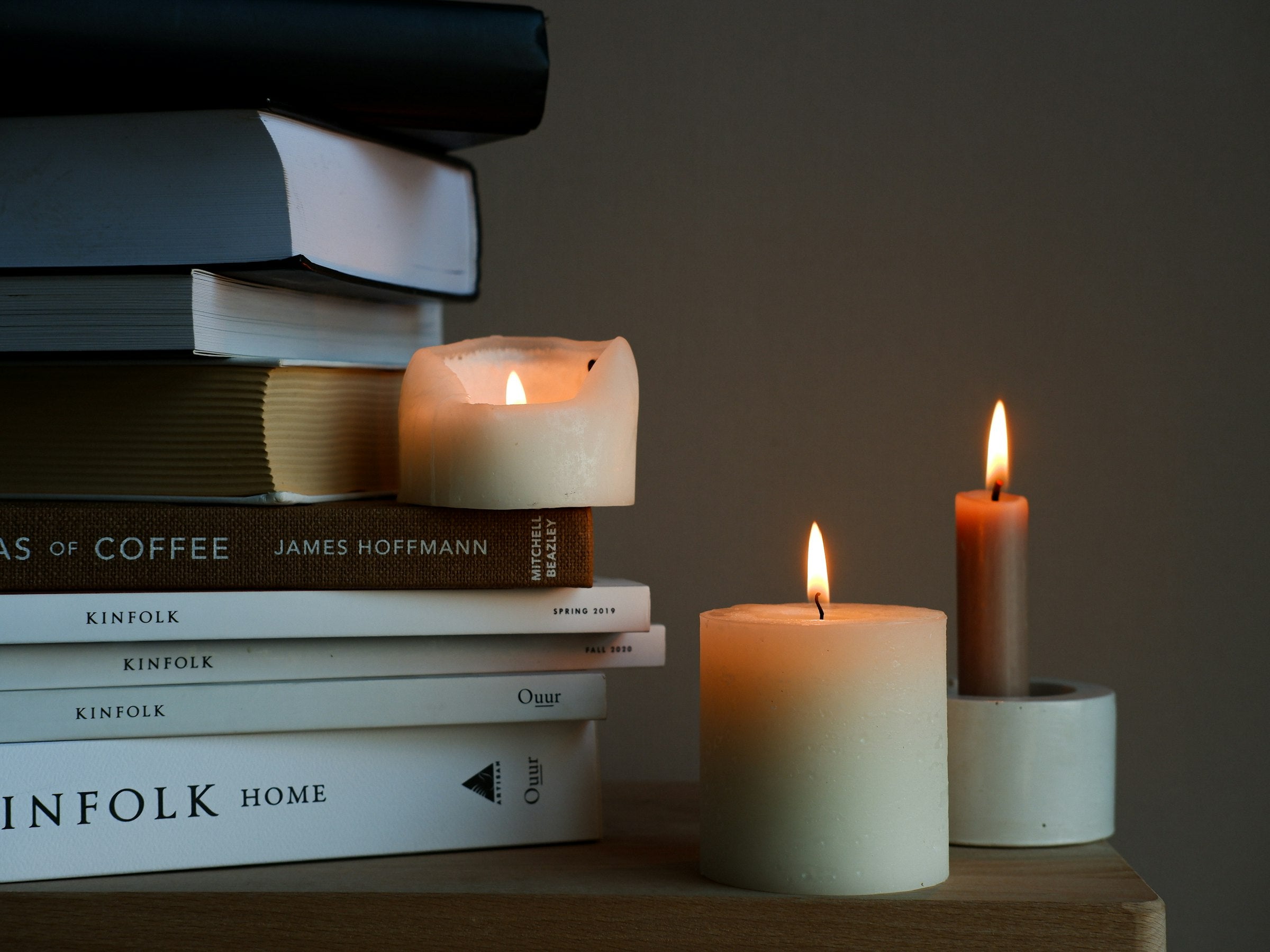 Cozy stack of books with lit candles - Quill Guides homepage banner